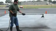 A professional applicator applies coal-tar-based sealcoat to a test plot used to measure emission of polycyclic aromatic carbons (PAHs) into the air