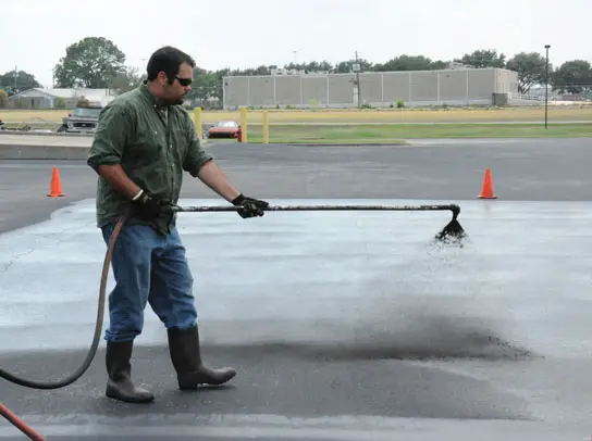A professional applicator applies coal-tar-based sealcoat to a test plot used to measure emission of polycyclic aromatic carbons (PAHs) into the air A professional applicator applies coal-tar-based sealcoat to a test plot used to measure emission of polycyclic aromatic carbons (PAHs) into the air